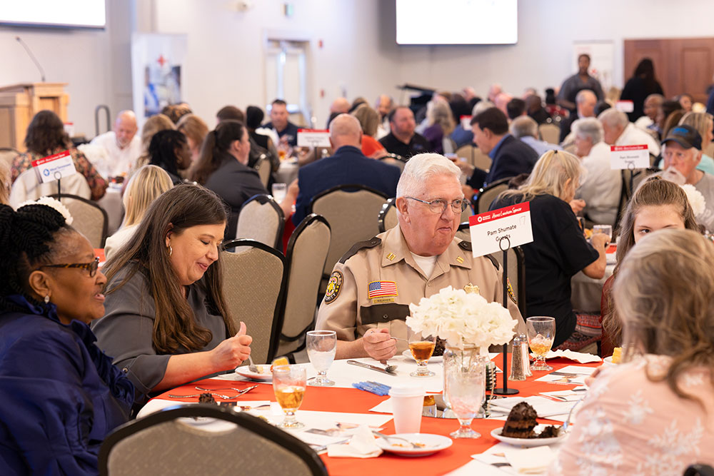 Guests eating and talking at dinner tables at the Mid-West Tennessee Heroes Luncheon..