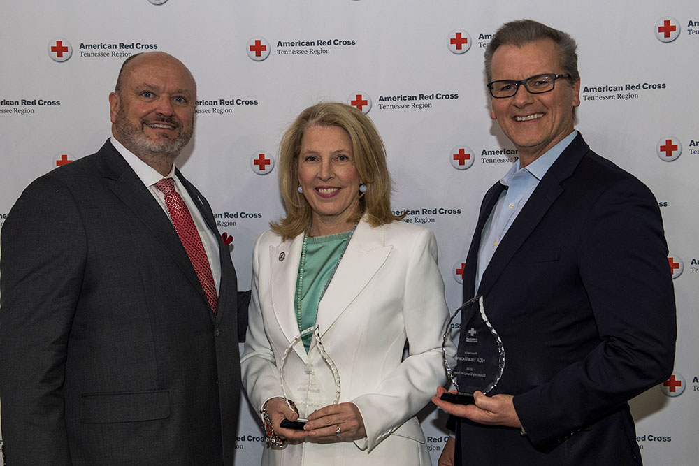 three people holding awards received at lifesaver luncheon event.