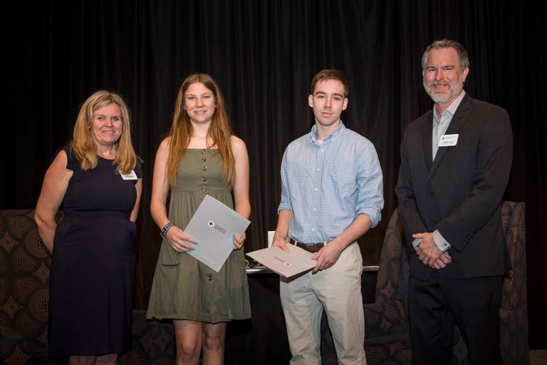 four people smiling posing for picture with awards in hand