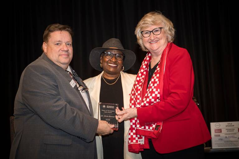 Three people holding an award smiling