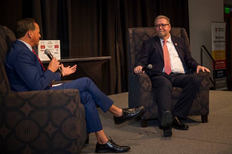 two men talking to each other sitting on chairs with microphones