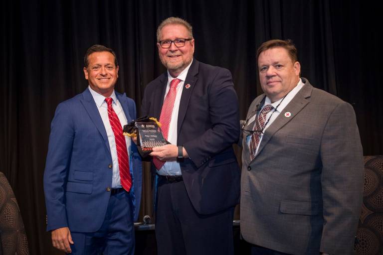 Three men holding award smiling 