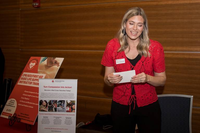 red cross volunteer at a table with pamphlets on table