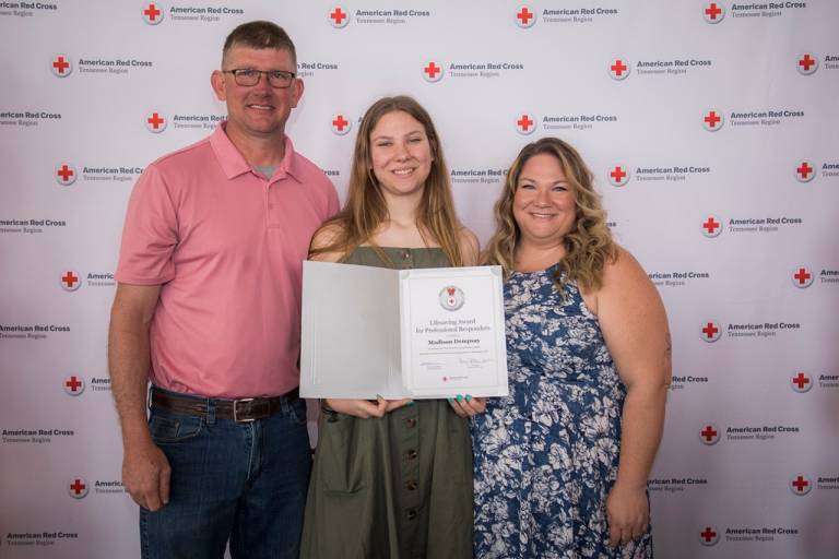 student with parents posing with an award