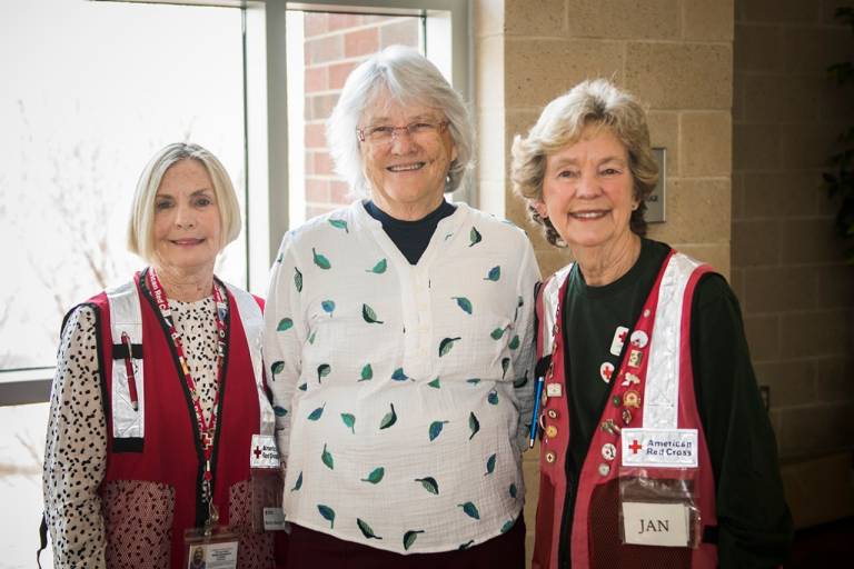 two red cross volunteers in red vest with guest