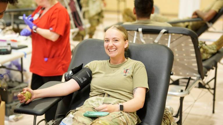 Woman in military uniform smiles while donating blood