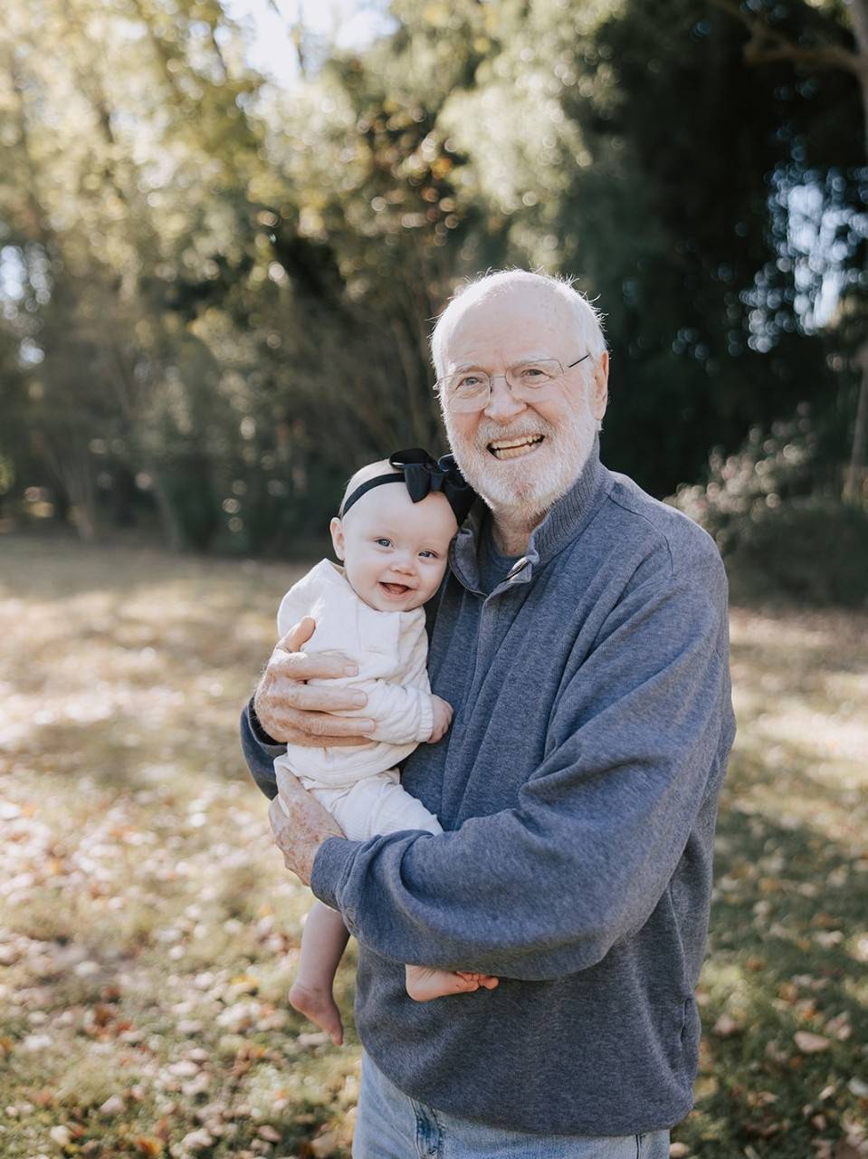 John stands outside holding baby in his arms