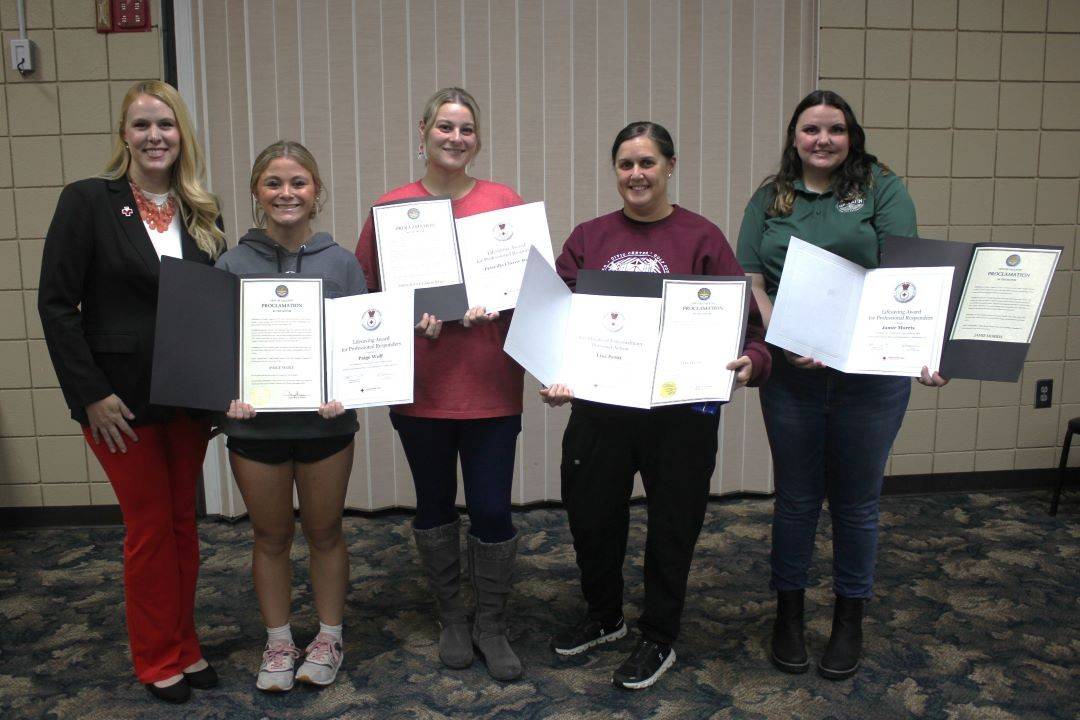 Group of people stand holding Red Cross awards