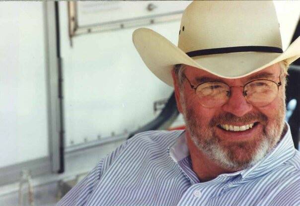 Man in cowboy hat smiles while looking off camera