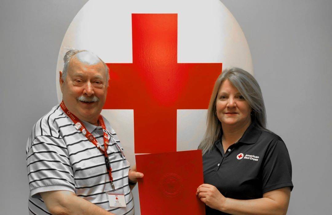 Man and woman stand side by side holding award in between them