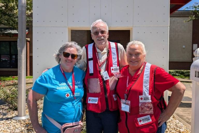 Three Red Cross volunteers stand side by side
