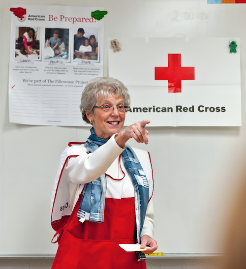 Red Cross volunteer wearing a Red Cross vest giving a presentation in front of a class