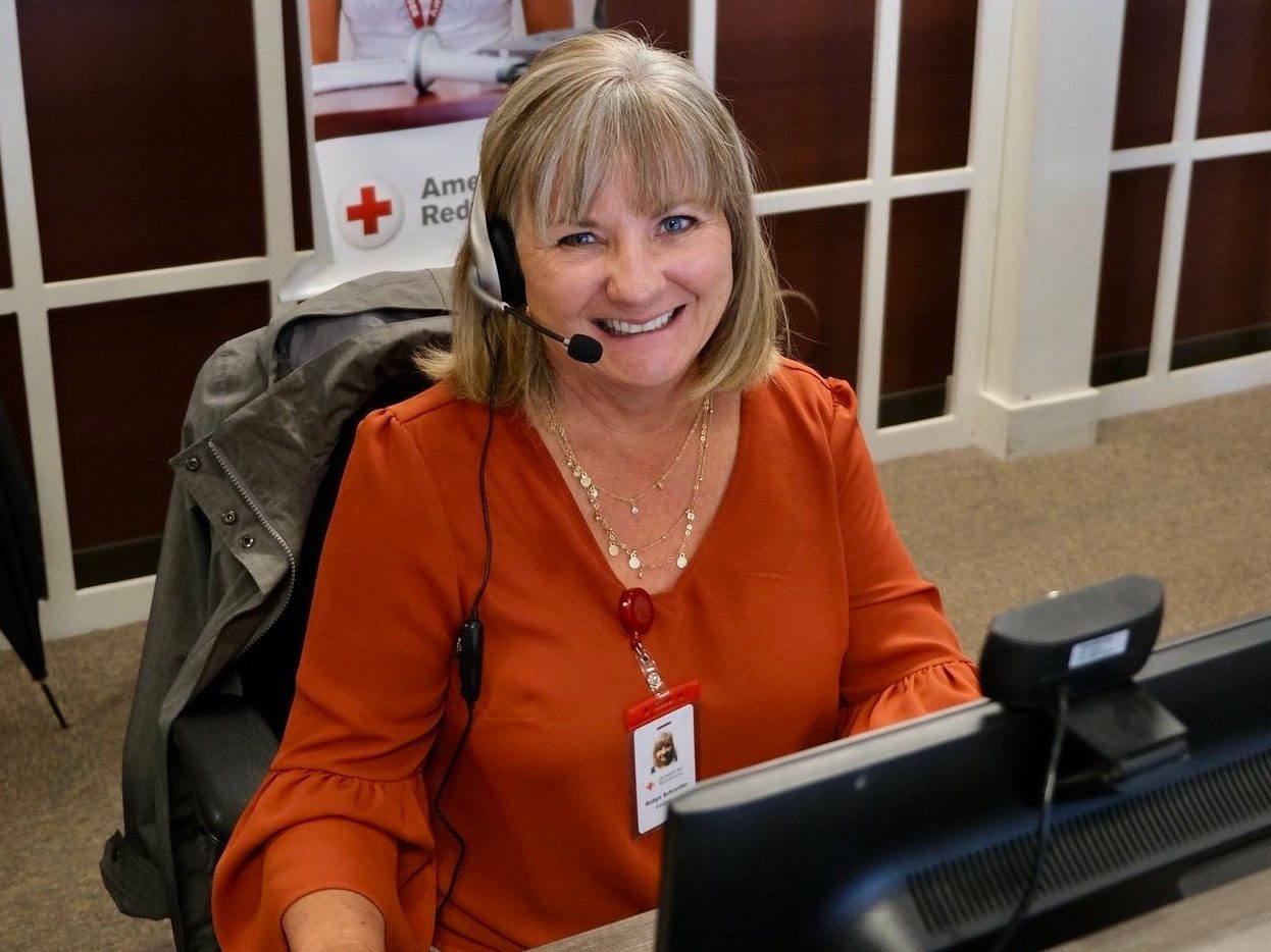 Woman sitting in chair at desk wearing phone headset smiling for camera