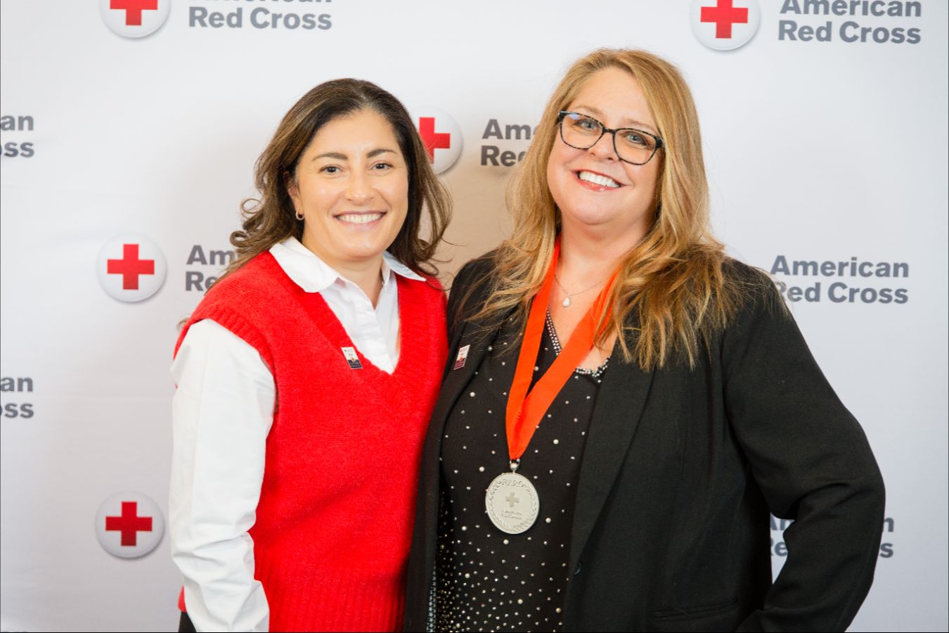 Two people posing for a picture, hugging each other with one holding an award