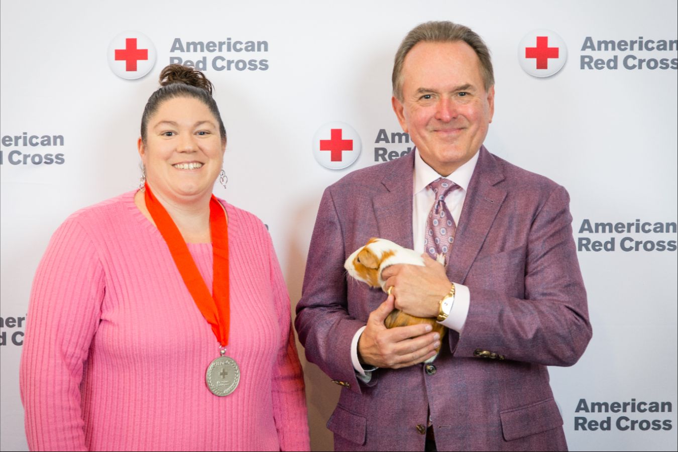 Two people posing for a picture, hugging each other with one holding an award