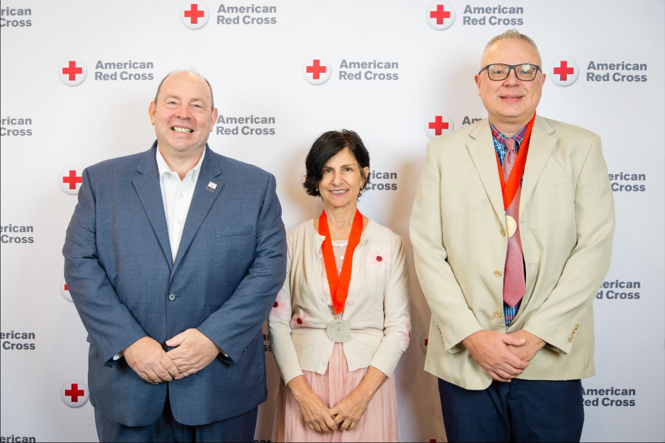 Three people posing for a picture with two people wearing medals