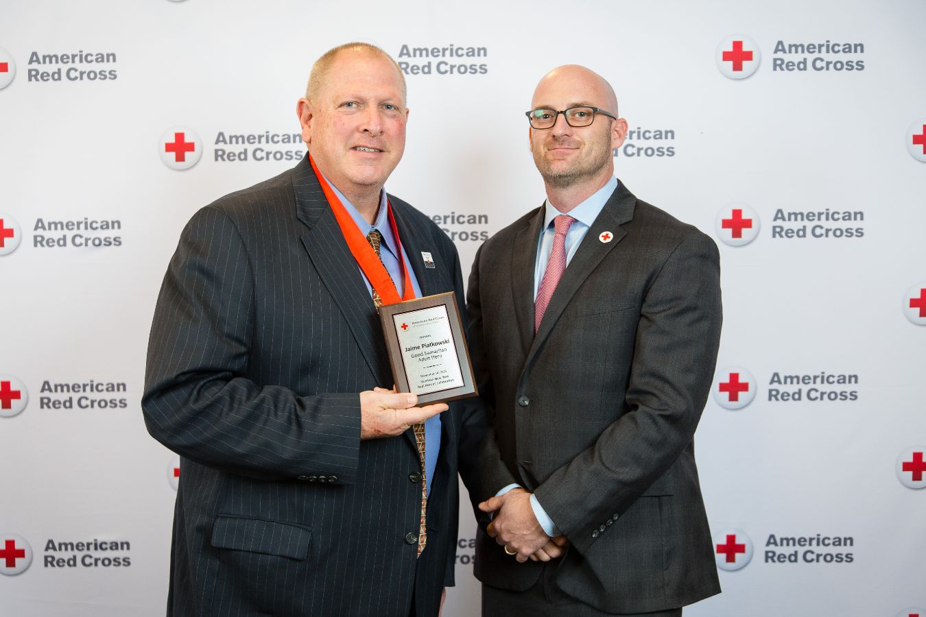 Two people posing for a picture, hugging each other with one holding an award