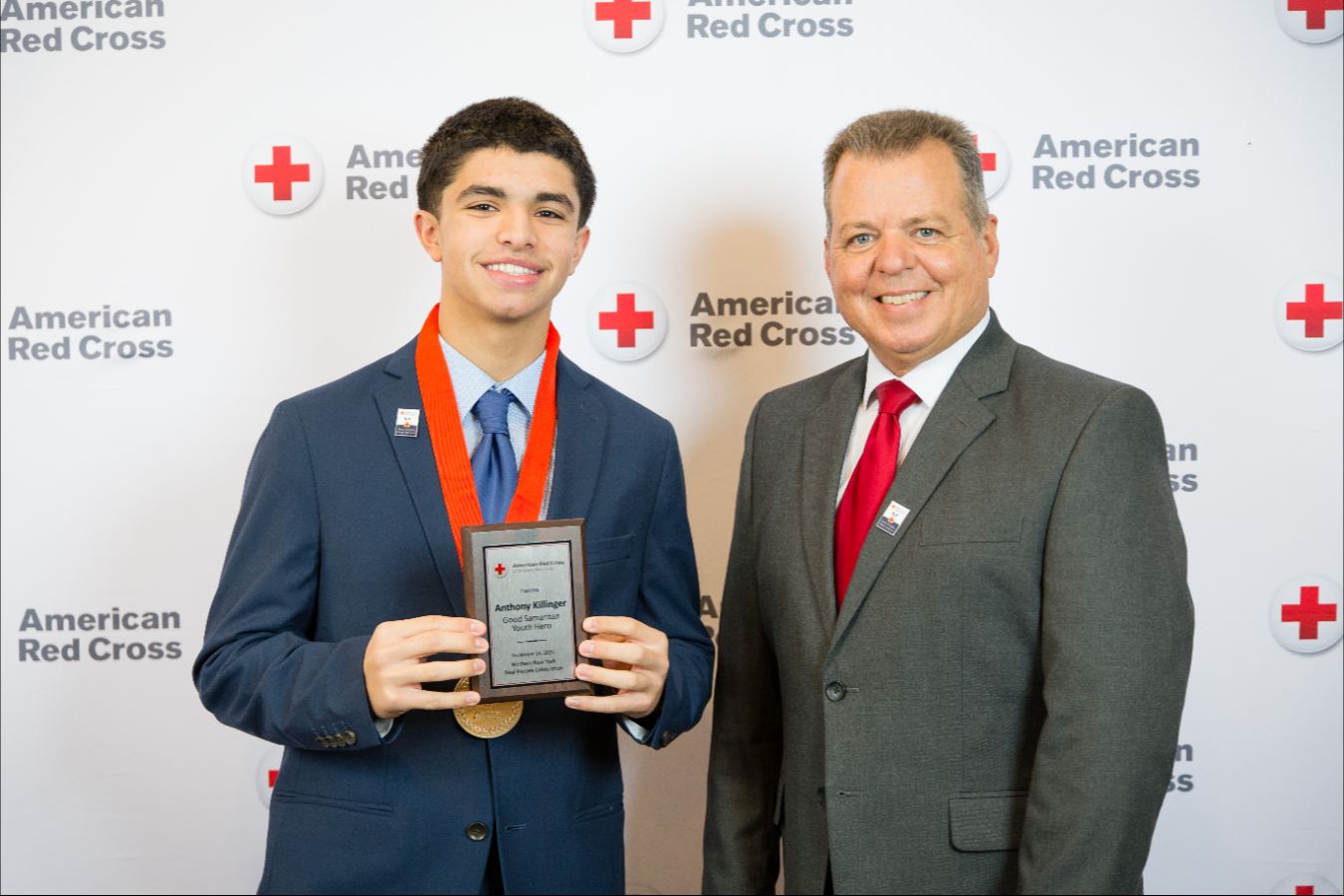 Two people posing for a picture, hugging each other with one holding an award