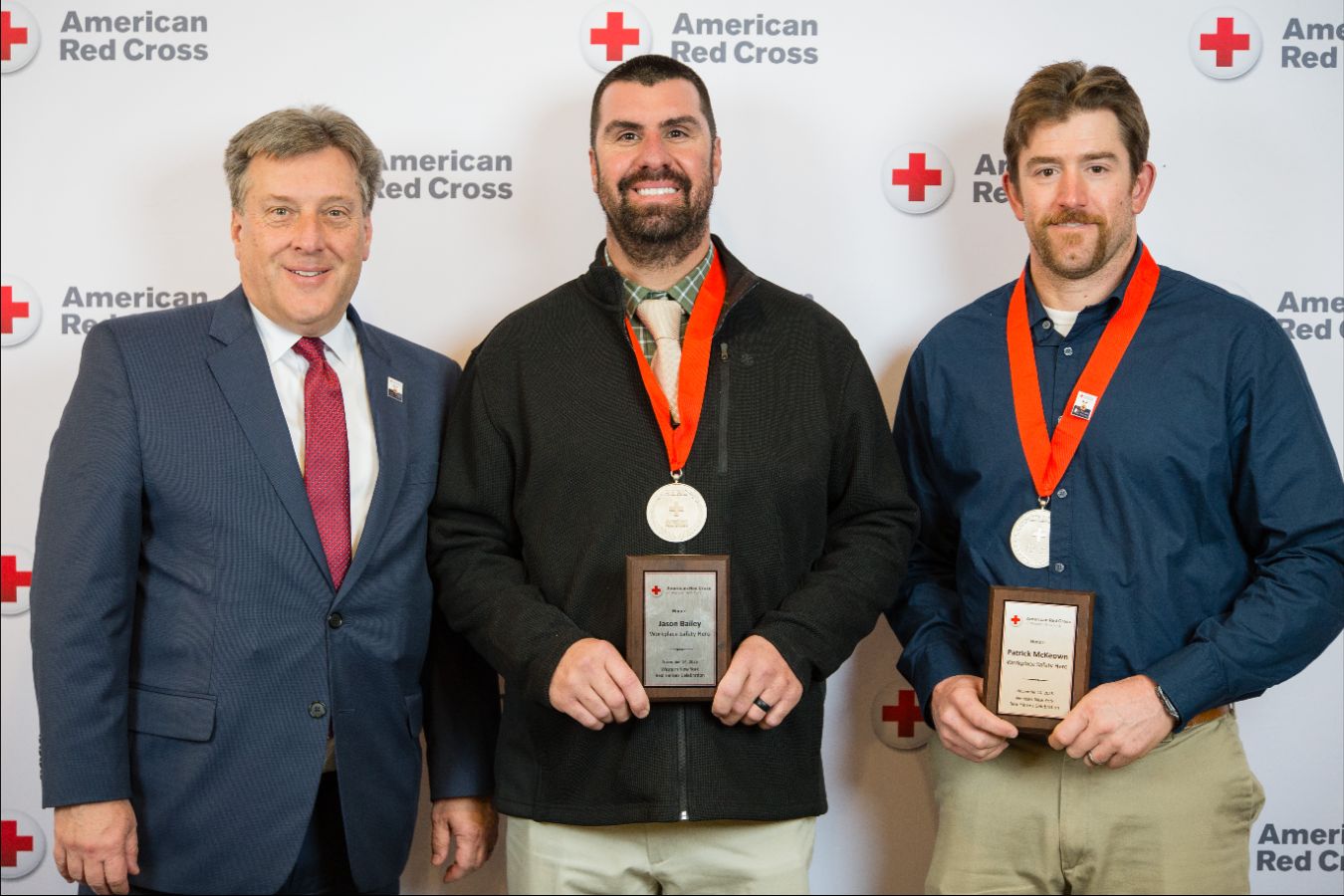 Three people posing for a picture with two wearing medals.
