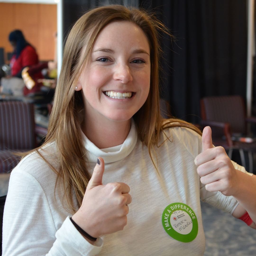 female blood donor giving thumbs up to the camera