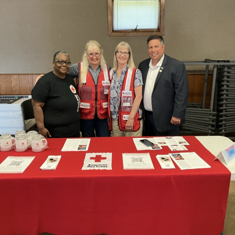 red cross volunteers stand behind table