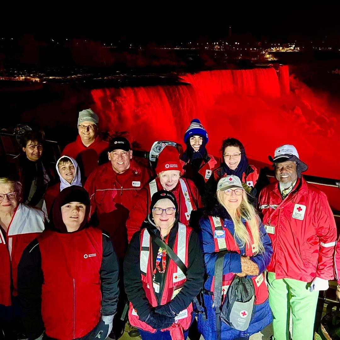 group of people in front of waterfall lit up red