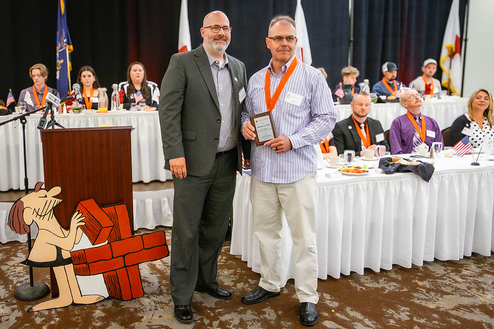workplace safety hero holds up his award at the Real Heroes Event.