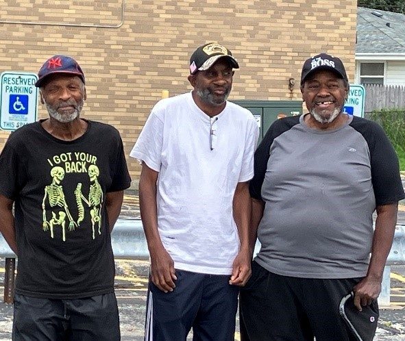 Three men standing side by side smiling 