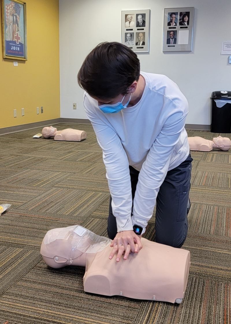 a person wearing a mask performing CPR on a mannequin