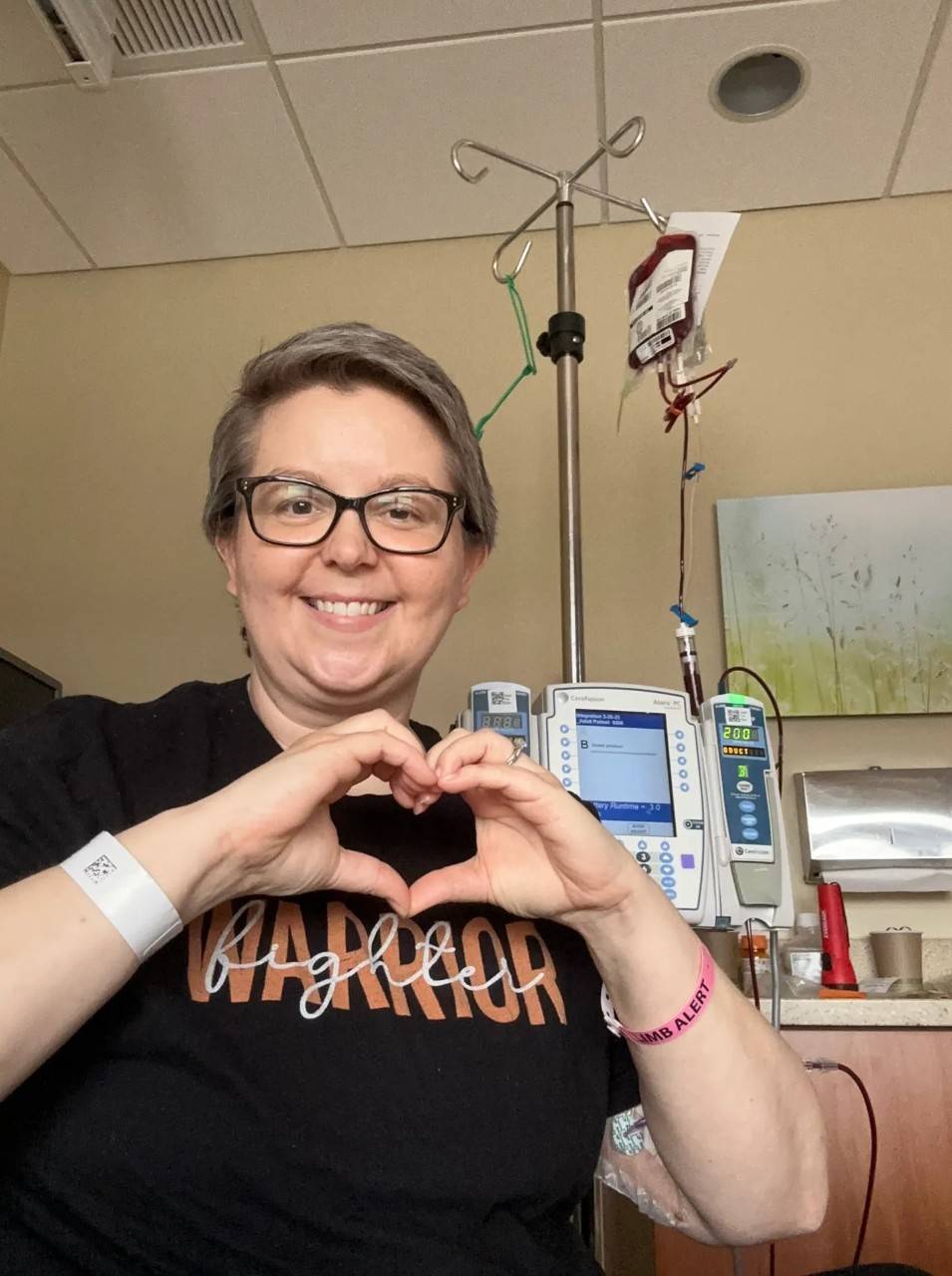 Woman makes heart with hands while in hospital