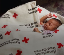 baby sleeps in red cross blanket