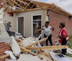 volunteer and resident look over damage after a tornado