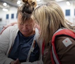 a Red Cross volunteer comforts a woman in a Red Cross shelter in California