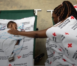 Woman and baby on cots in a Red Cross shelter