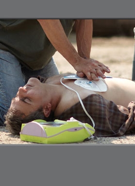 a person in jeans and tee shirt is doing CPR on a person lying down
