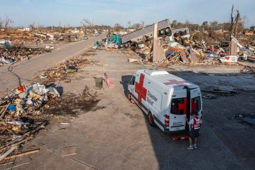 Red Cross emergency response vehicle parked among massive debris of tornado in Mississippi