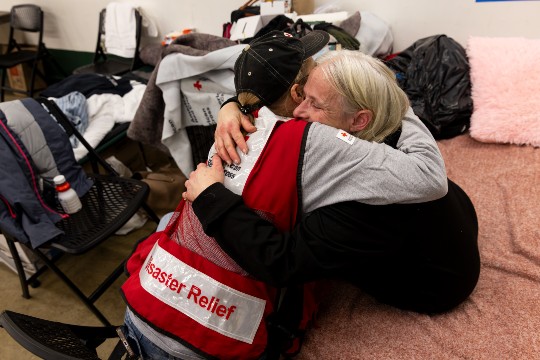 Red Cross volunteer shares a hug with a shelter resident
