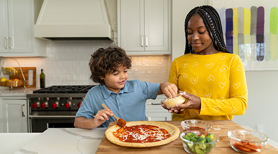A babysitter helps a child make pizza