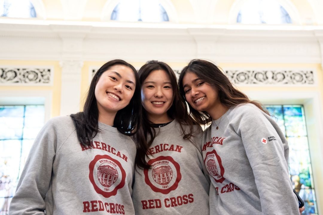 Three girls stand together in Red Cross Sweatshirts