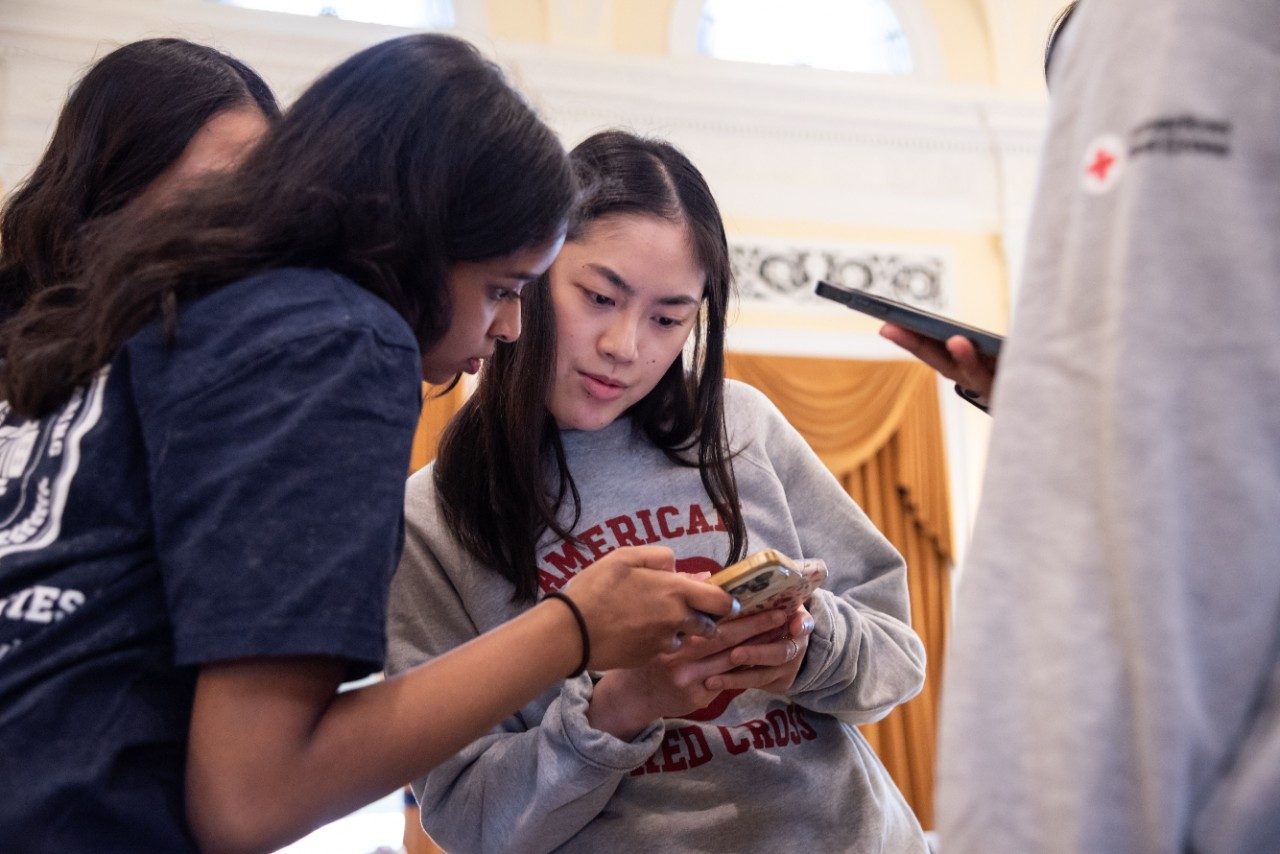 youth stand together looking at cell phone