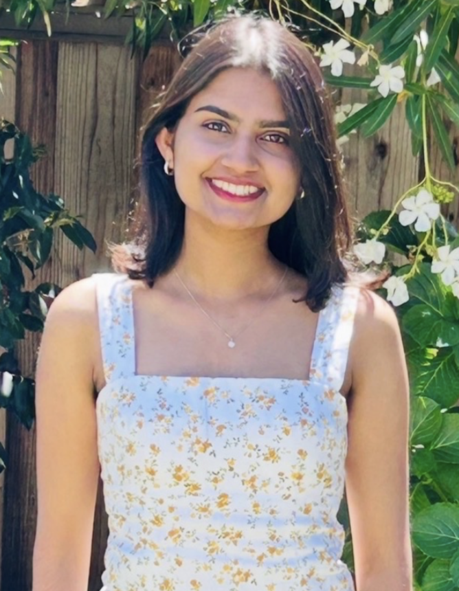 Aditi Kiran, a young woman wearing a white summer dress, with dark brown hair. 