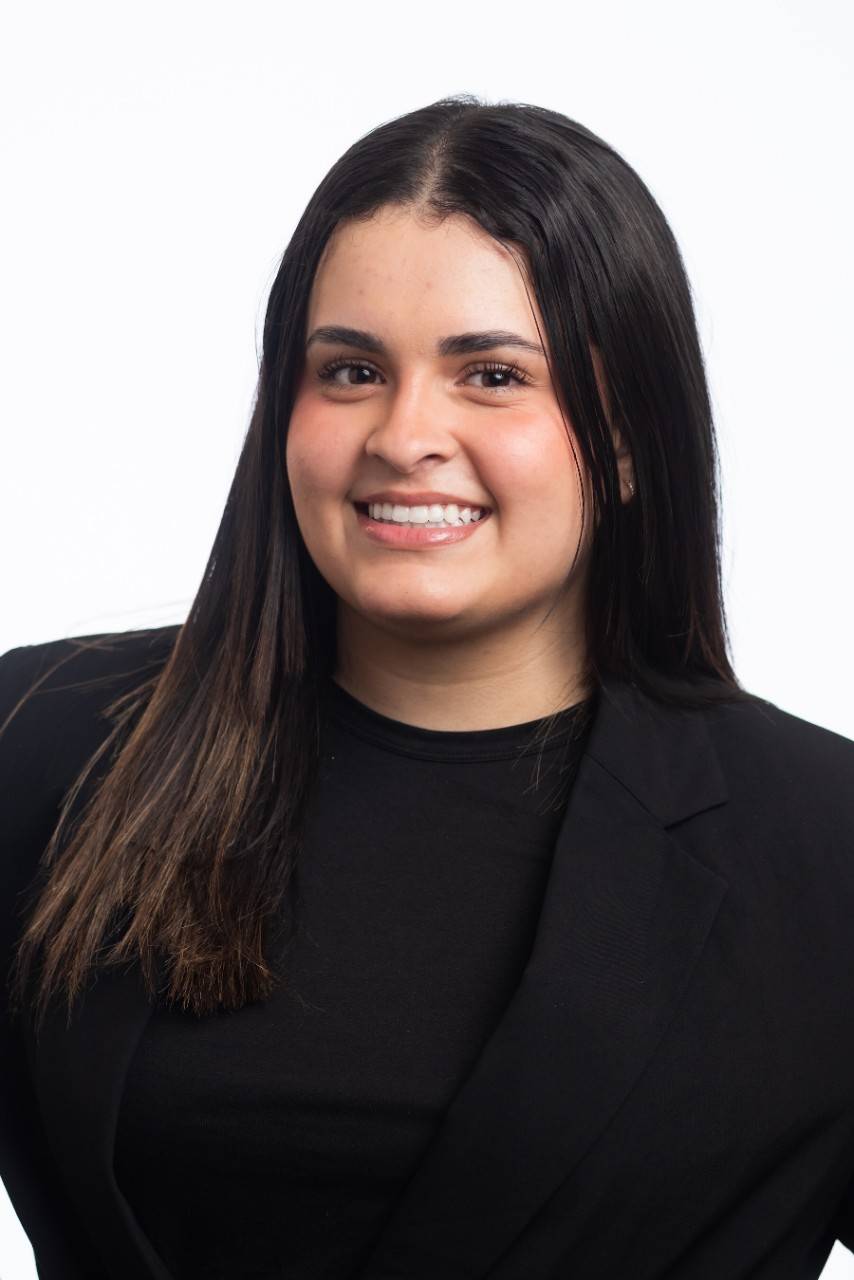 Dianne Estevez Escalera, a young woman wearing a black suit jacket and black blouse, with dark brown hair. 