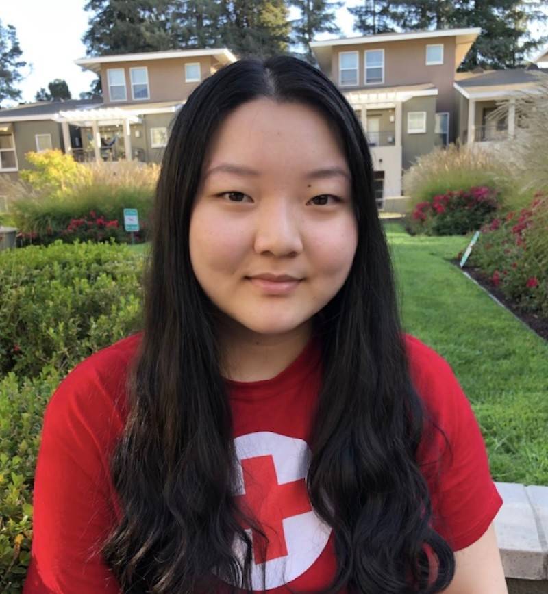 Kelsey Mu, a young woman wearing a red Red Cross t-shirt, with long black hair. 