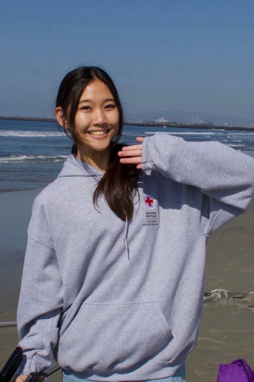 Lauren Ko, a young woman wearing a gray Red Cross hoodie with dark brown hair in a ponytail.