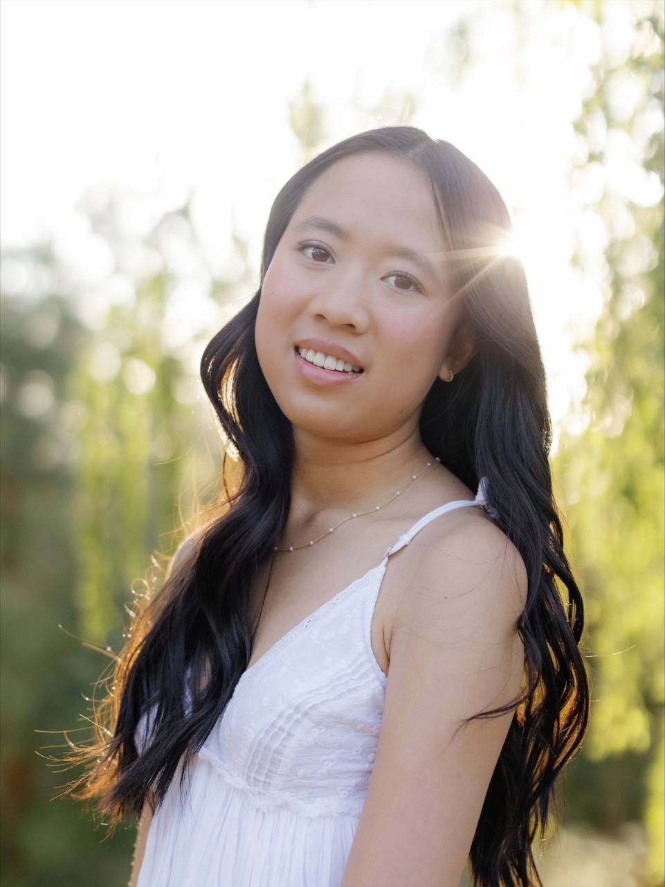 Olivia Ho, a young woman wearing a white summer dress, with black hair. 