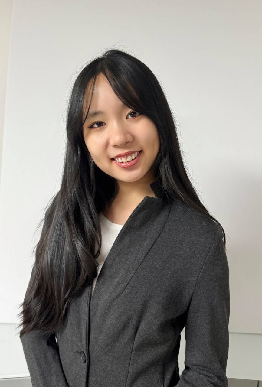 Sophia Yang, a young woman wearing a dark gray suit jacket and white blouse, with black hair. 