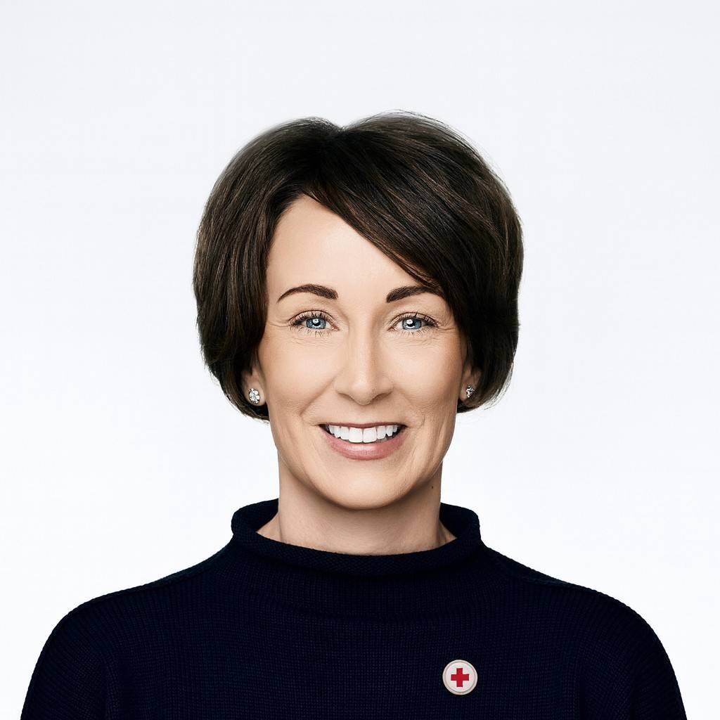 Headshot of Sara Horein, a woman with short, dark brown hair smiling wearing a black shirt with a Red Cross pin