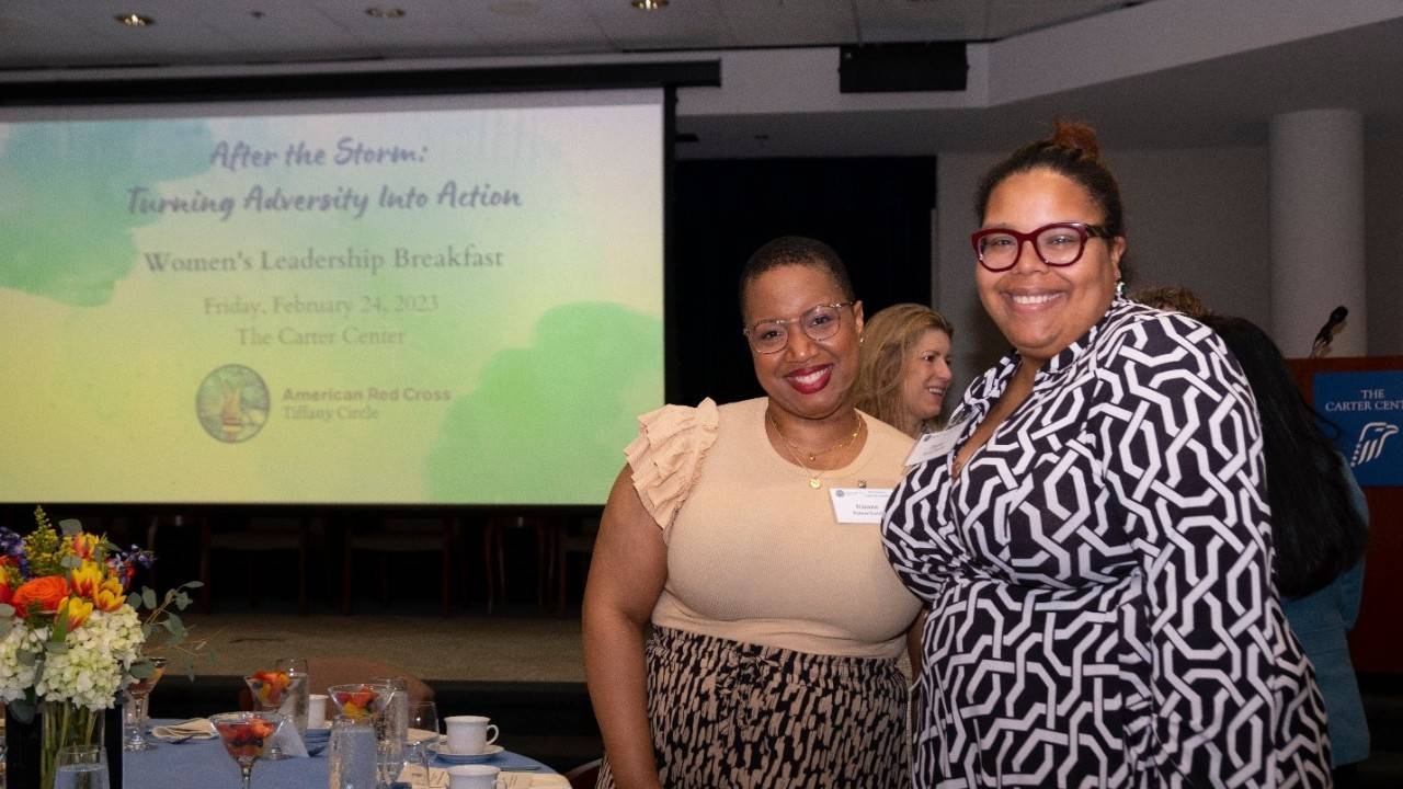 Two women standing in front of presentation at Tiffany Circle Georgia Region Women’s Leadership Breakfast