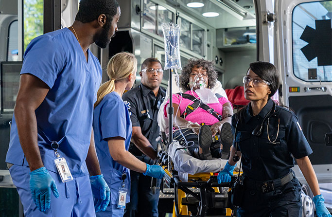 Emergency responders preparing a patient with an oxygen mask for ambulance transport, coordinating urgent care at the back of the vehicle during a critical medical situation.