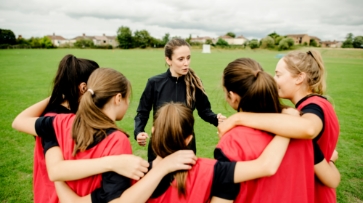 Coach teaching students on the field about first aid